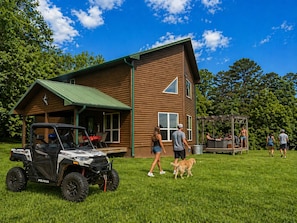 Una baita di legno con veranda coperta, area patio e angolo barbecue.