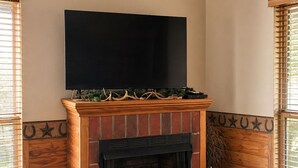 A fireplace with a TV above it, a rug, and a candle on a table.