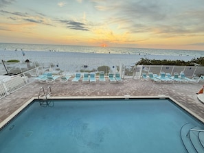 Ein Poolbereich mit Liegestühlen und Blick auf den Strand bei Sonnenuntergang.