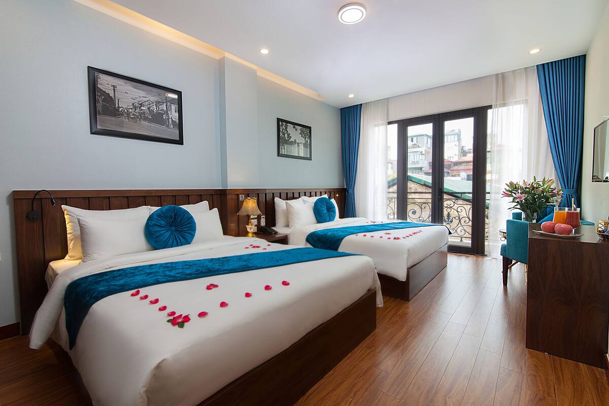 A hotel room with two beds, a balcony, and a view of the city.