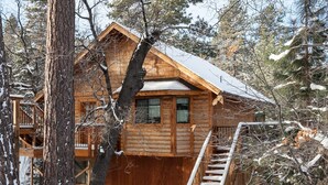 A wooden cabin with a balcony and a staircase leading to the entrance.