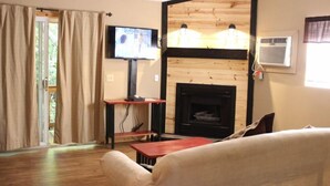 Una sala de estar con chimenea, televisión y pared de madera.