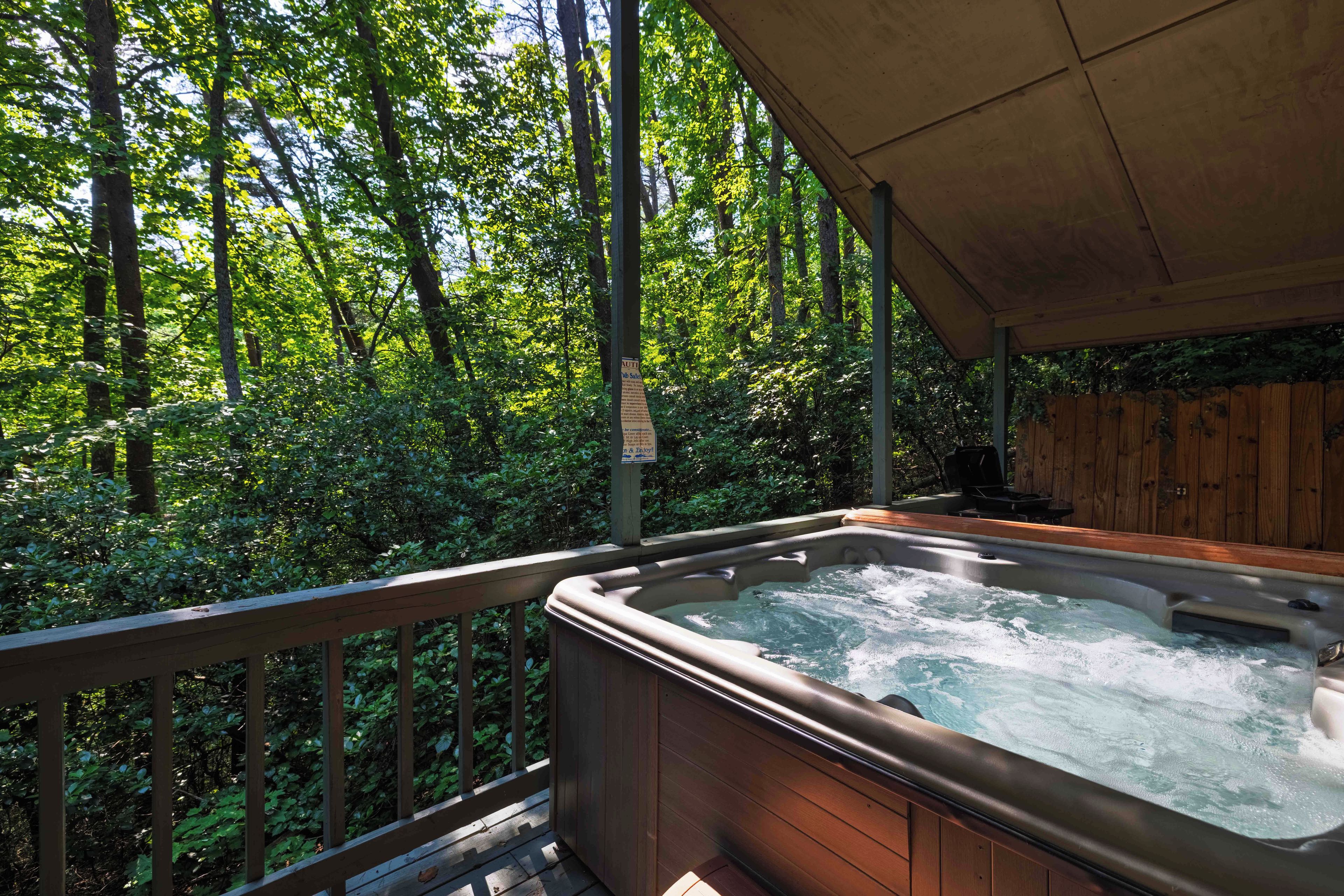 A hot tub on a wooden deck surrounded by a forest.