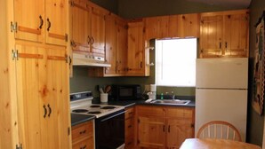 Una cocina compacta con armarios de madera, estufa, microondas y refrigerador.