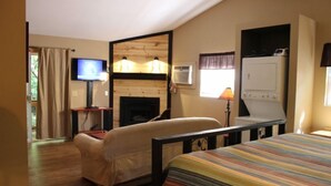 Una habitación acogedora con cama, sofá, televisión, chimenea y lavadora.