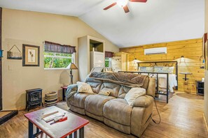 A cozy room with a sofa, a table with tools, a window with a view, and a ceiling fan. - Cherokee Ridge 7 - Pet Friendly Cottage All About Location, Location (Sautee Nacoochee)