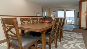 Un comedor con una mesa y sillas de madera, un cuenco decorativo sobre la mesa, y vistas al exterior a través de una puerta de cristal.
