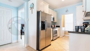 Una cocina moderna con armarios blancos, un refrigerador de acero inoxidable, un microondas y un horno.