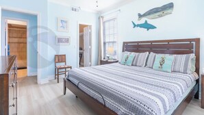Un dormitorio con una cama, ventilador de techo, armario, silla y ventana.