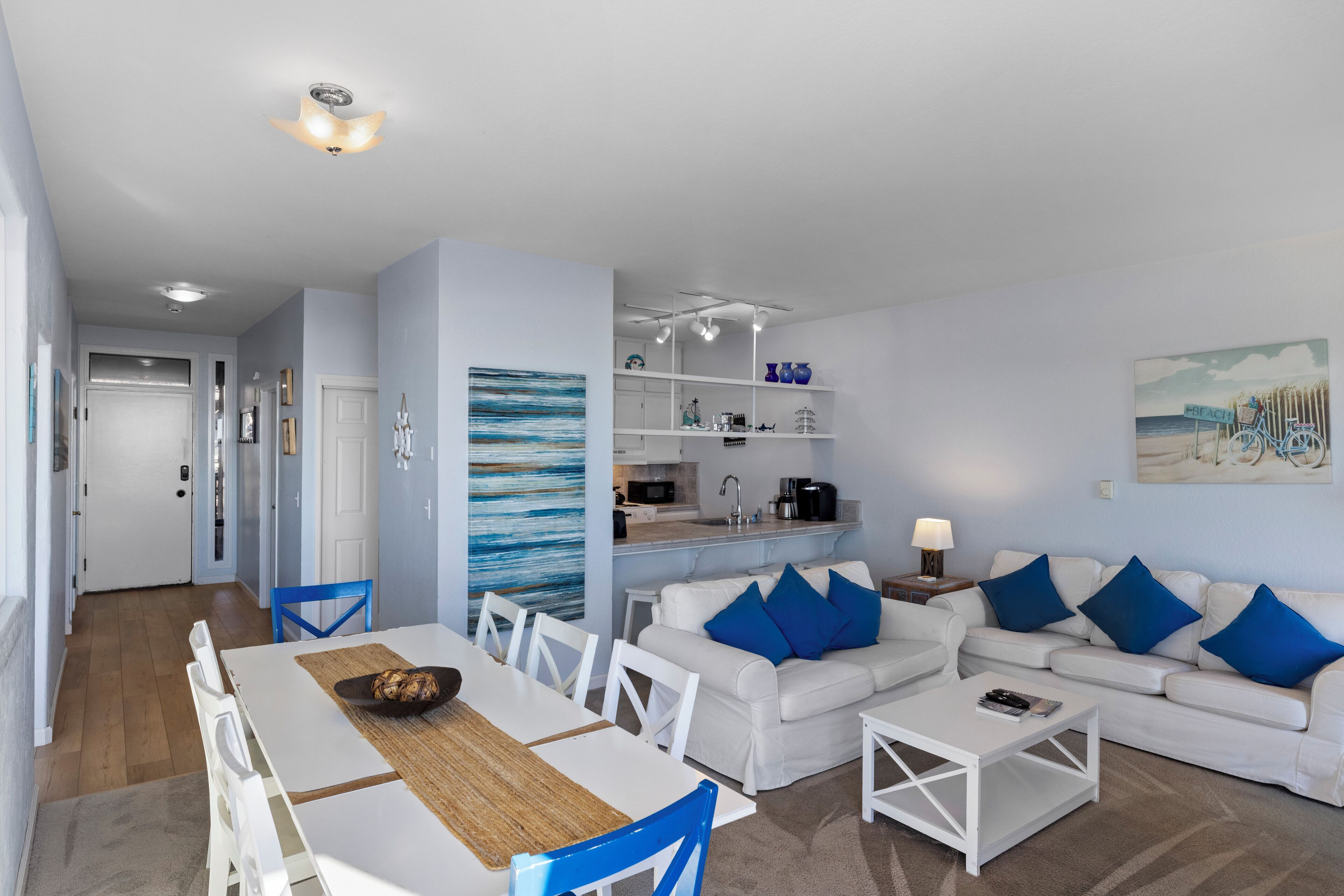 A modern living room with white furniture, a dining area, and a kitchen.