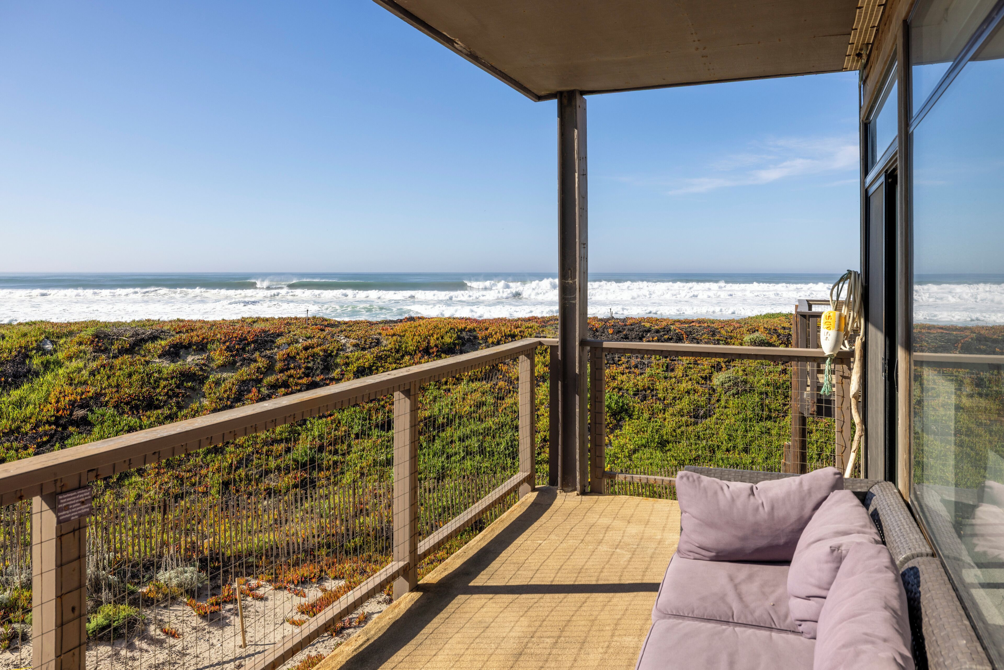 Un balcone con vista sull'oceano, un'area salotto con cuscini e una ringhiera.