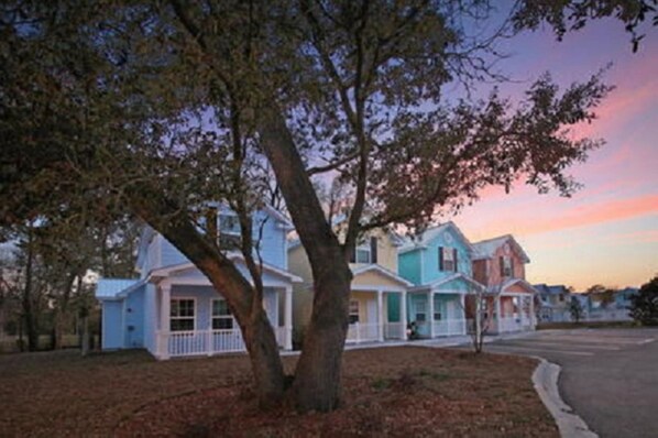 A row of two-story houses with a tree in the foreground.