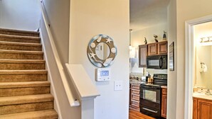 Una escalera conduce a una cocina con armarios de madera, un microondas y un horno.