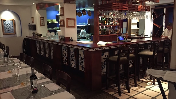 A bar area with a counter, stools, and a wine bottle on the table. - Deluxe Two-Bedroom Apartment in Escalante, San Jose center. (San José)