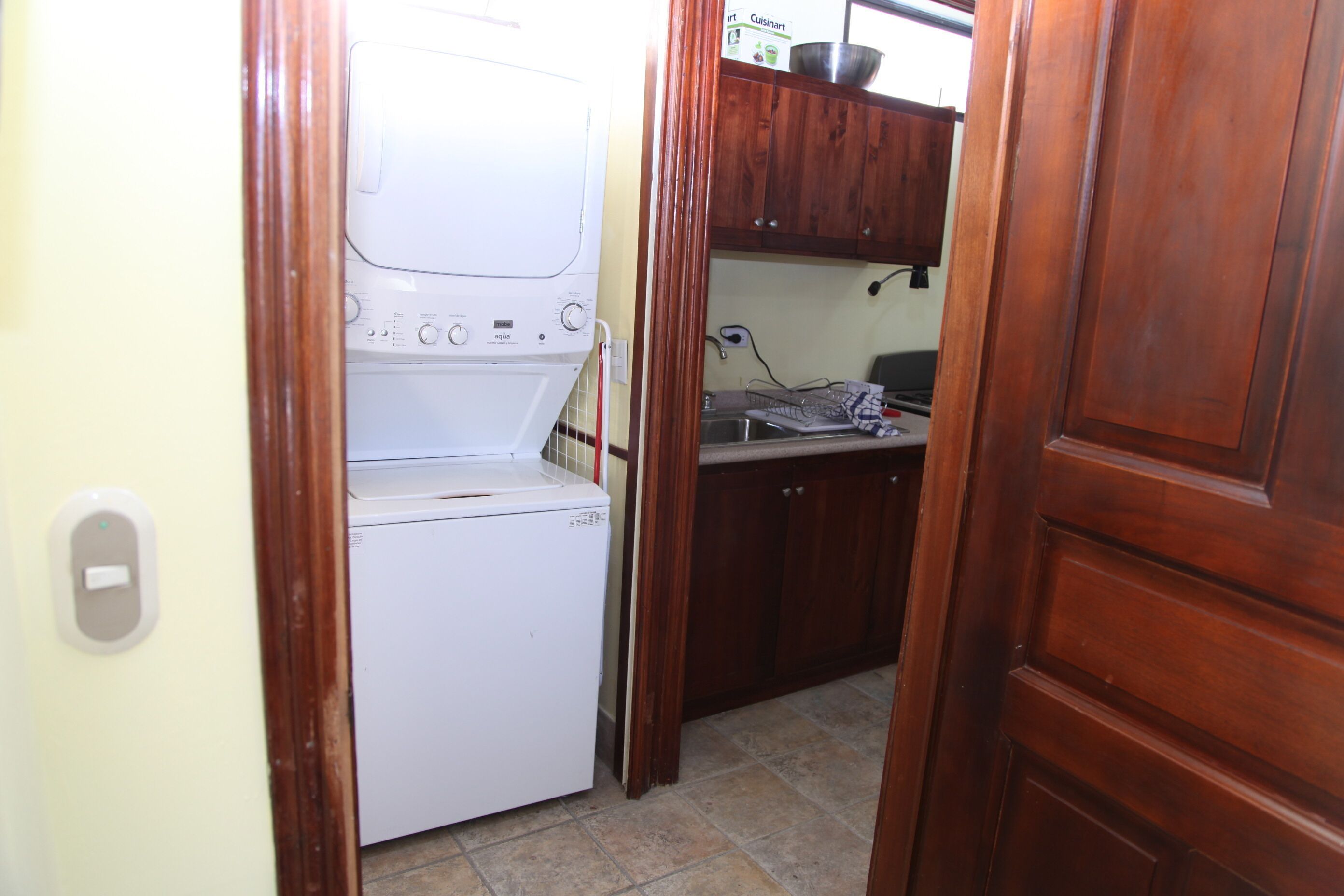 A compact kitchen with a built-in washing machine, a sink, and wooden cabinets.