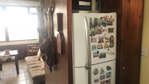 A kitchen with a refrigerator covered in magnets, a wooden door, and a window with curtains. - Deluxe Two-Bedroom Apartment in Escalante, San Jose center. (San José)