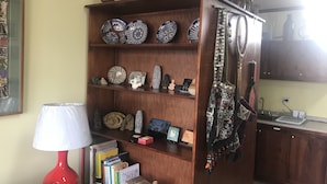 A wooden bookshelf with decorative plates, small sculptures, and books. - Deluxe Two-Bedroom Apartment in Escalante, San Jose center. (San José)