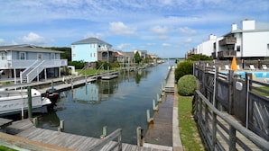 A canal with boats docked, wooden walkways, and houses along the water.