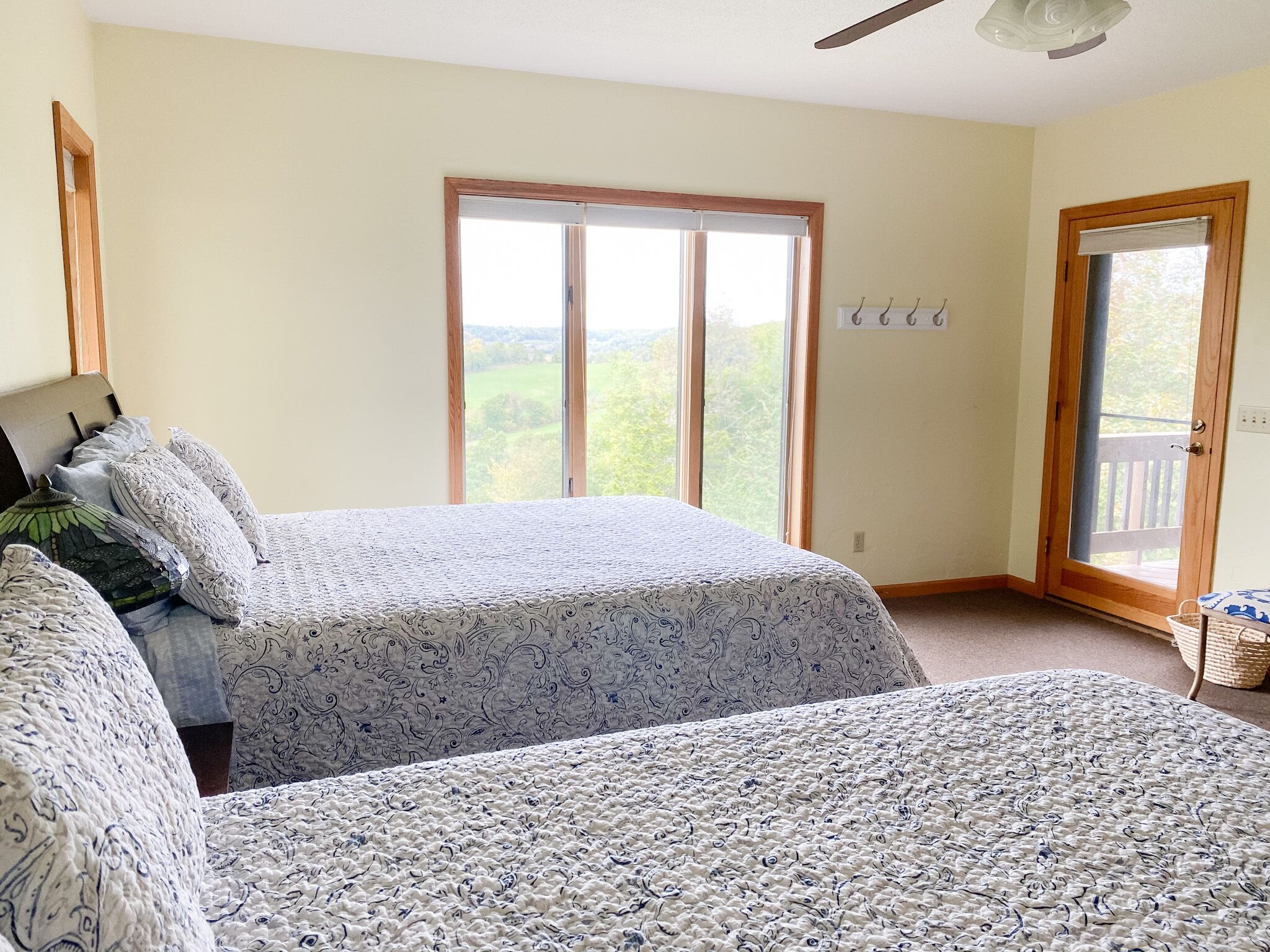 Ein Schlafzimmer mit zwei Betten, einem großen Fenster und einer Tür, die auf einen Balkon führt.