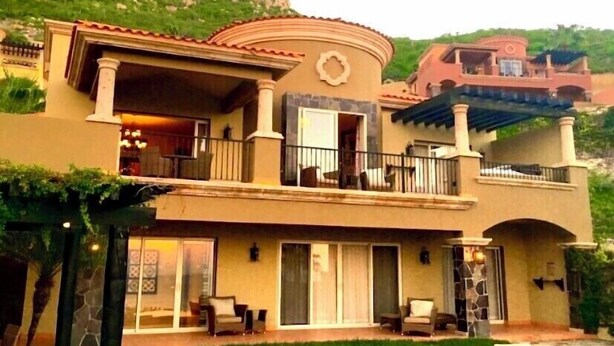 A two-story house with a balcony, a stone pillar, and a patio area.