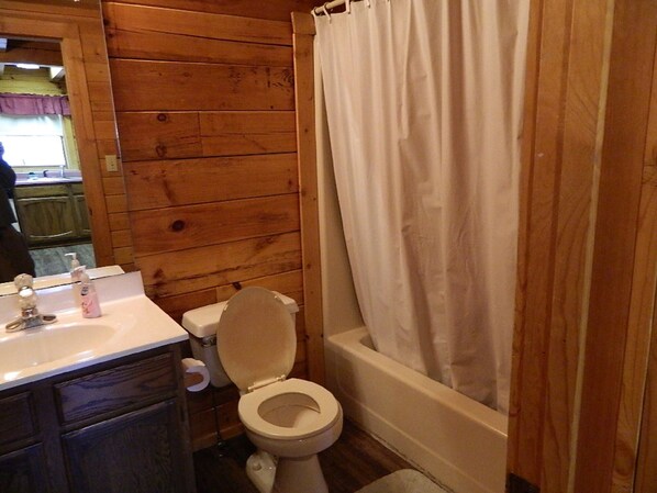 Un baño con paneles de madera, un inodoro, un lavamanos y una bañera.