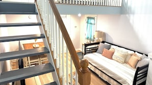Une chambre à coucher avec un lit, un escalier en bois et une fenêtre avec des rideaux.