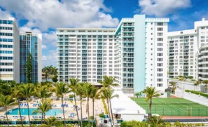 A hotel with multiple high-rise buildings, a swimming pool, and tennis courts.