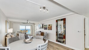 A spacious dining area with a round table, white chairs, and a ceiling fan. - 🏖️Escape to this Gulf front 2 BR / 2 BTH condo with swimming pool (Pensacola Beach)
