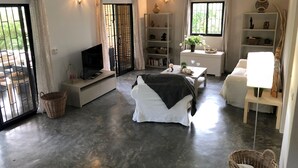 A spacious living area with a sofa, a television, a dining table, and a bookshelf. - La Belle Créole, home for 5, peaceful, close to the beaches (Las Galeras)