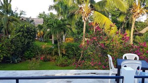 A lush garden with palm trees, flowering plants, and a thatched-roof structure. - La Belle Créole, home for 5, peaceful, close to the beaches (Las Galeras)