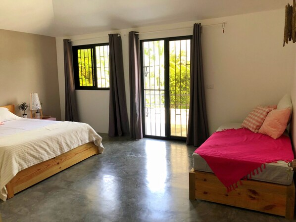Un dormitorio con dos camas, ventanas amplias y un balcón.
