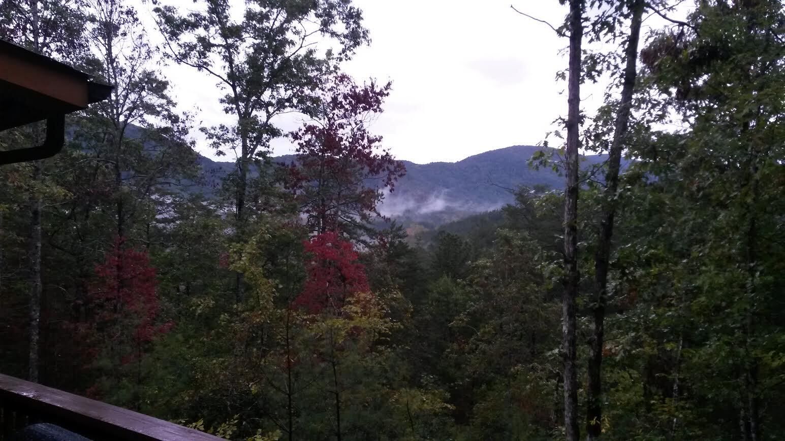 A forested mountain landscape with a wooden deck.