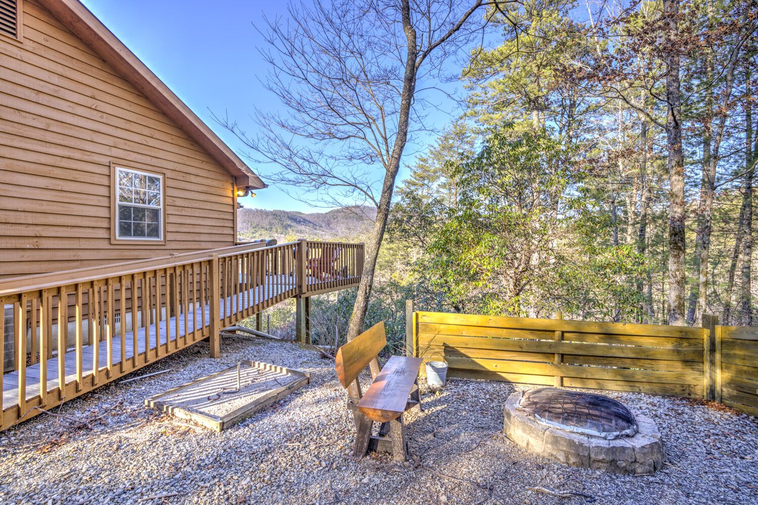 Une cabane en bois avec une terrasse, un foyer et un banc.