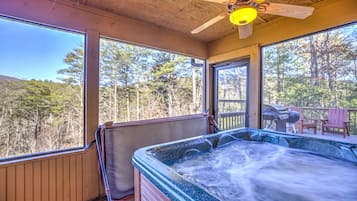 A hot tub in a wooden cabin with large windows overlooking a forest.