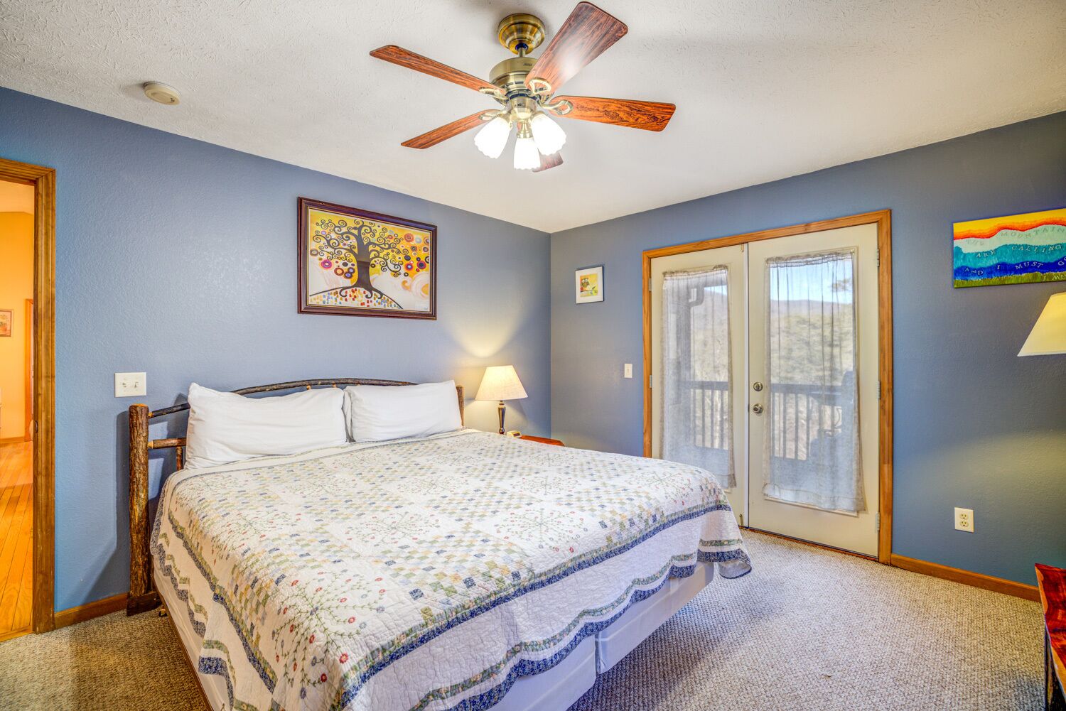 A bedroom with a bed, a ceiling fan, a door, and a window.