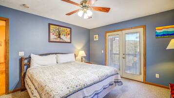A bedroom with a bed, a ceiling fan, a door, and a window.