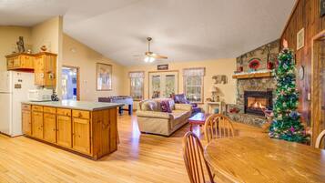 A spacious living area with a fireplace, a dining table, and a kitchen with wooden cabinets.