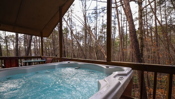 A hot tub on a wooden deck with a forest view.