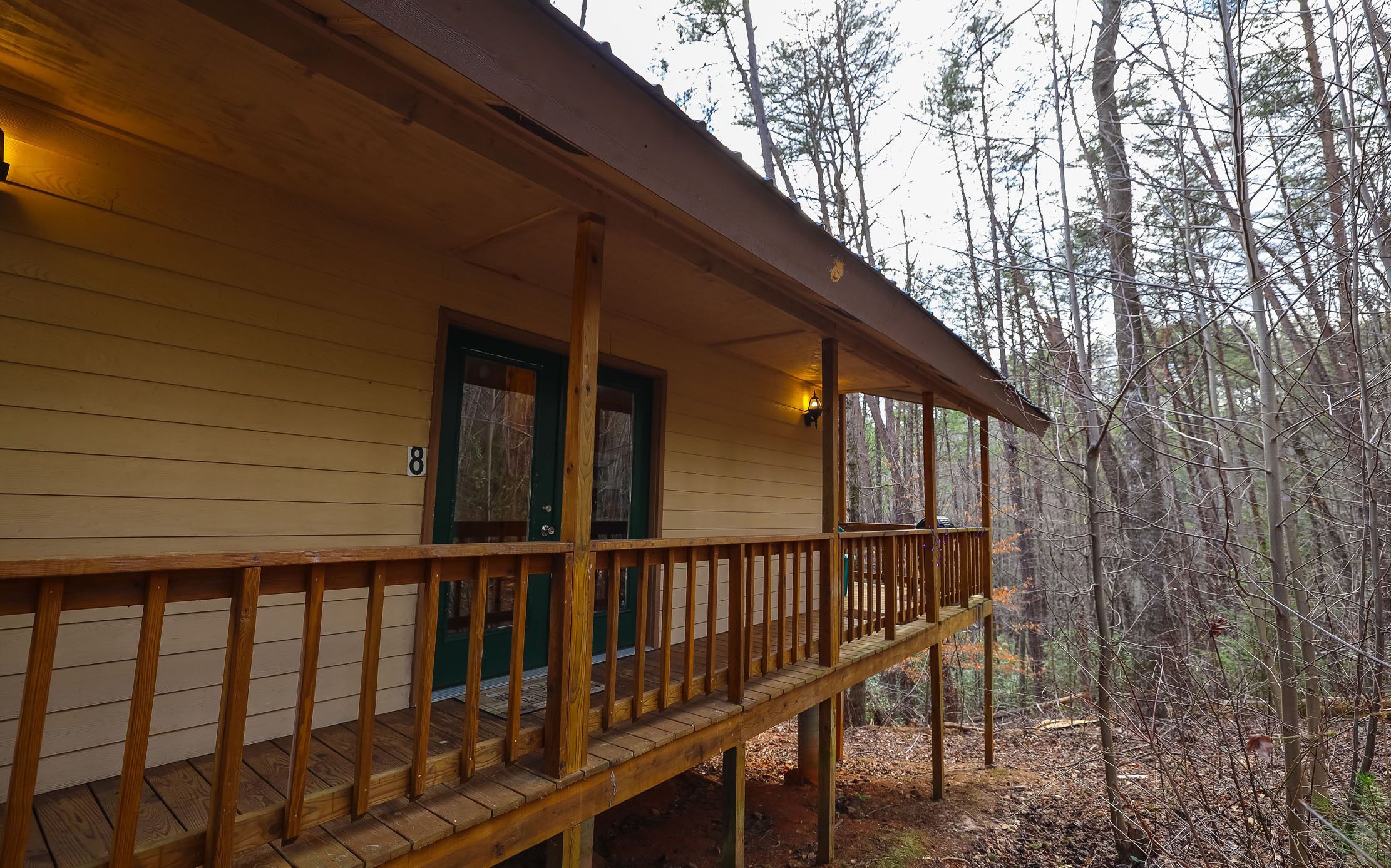 A wooden cabin with a balcony, a door, and a window.