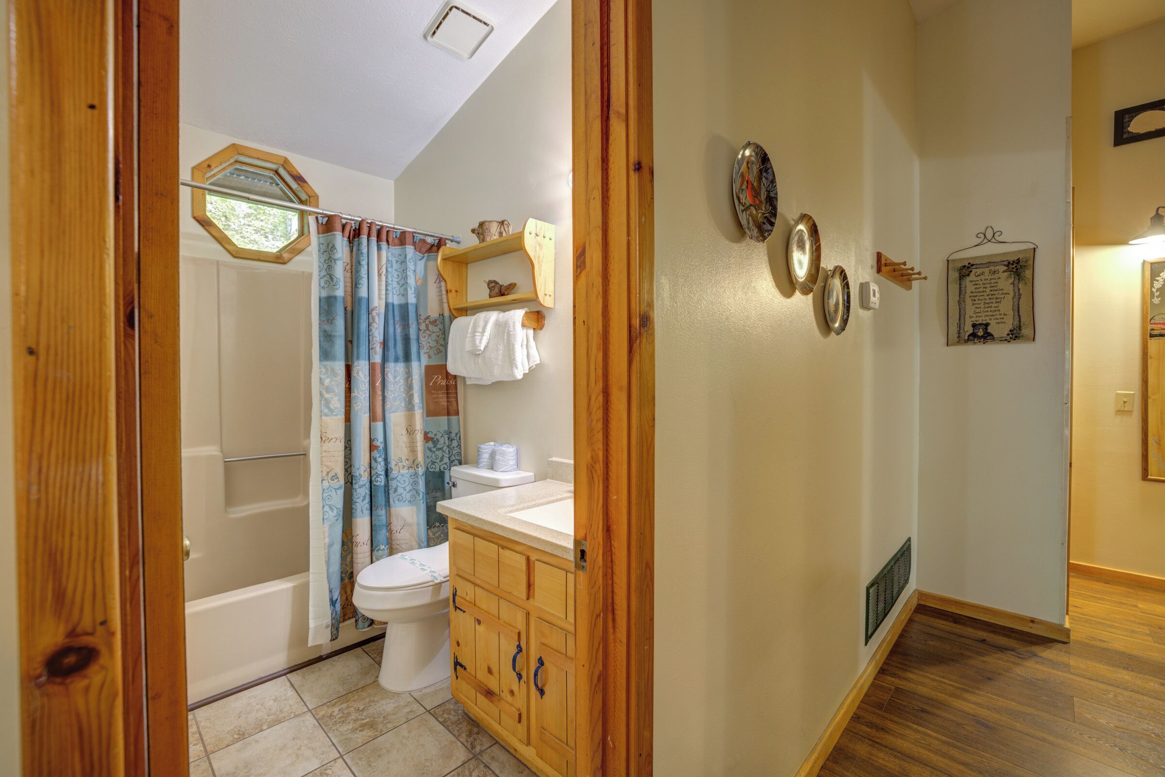 A bathroom with a wooden vanity, a toilet, a bathtub, and a shower curtain.