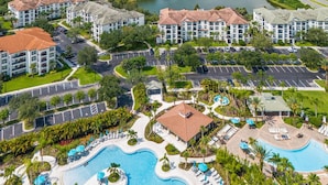 A resort with multiple buildings, a large swimming pool, and a lake in the background.