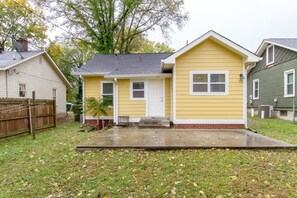 A single-story house with a front porch, a small front yard, and a wooden fence.