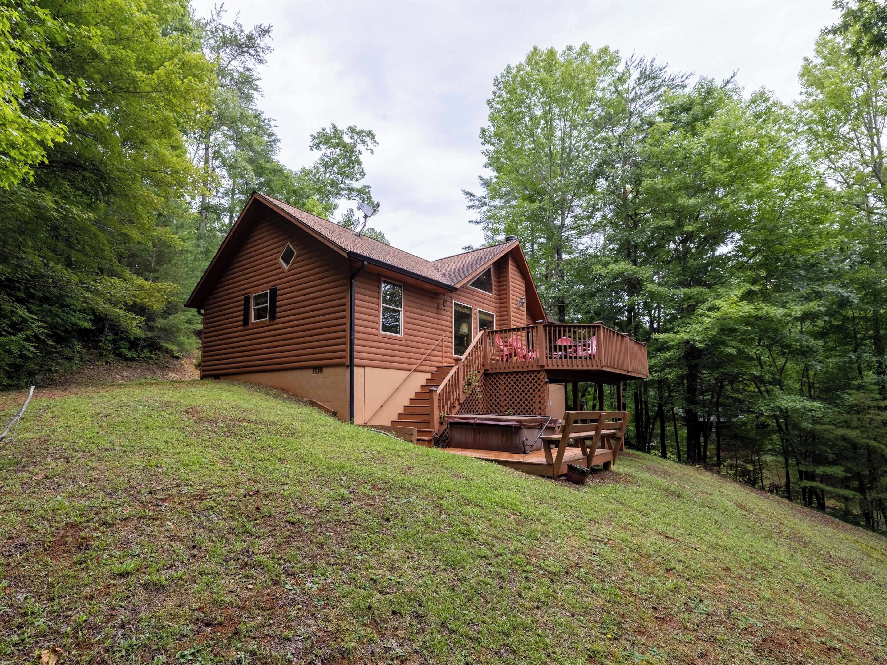 A log cabin with a deck and stairs leading to a porch.