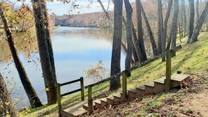 A wooden staircase leading down to a lake surrounded by trees with autumn leaves. - Stepping Stone Cabin (Page County)