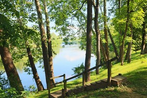 A wooden staircase leading down to a body of water, surrounded by trees. - Stepping Stone Cabin (Page County)