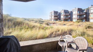Ein Blick auf ein Gebäude mit mehreren Balkonen und einer Holzterrasse mit Plastikstühlen.