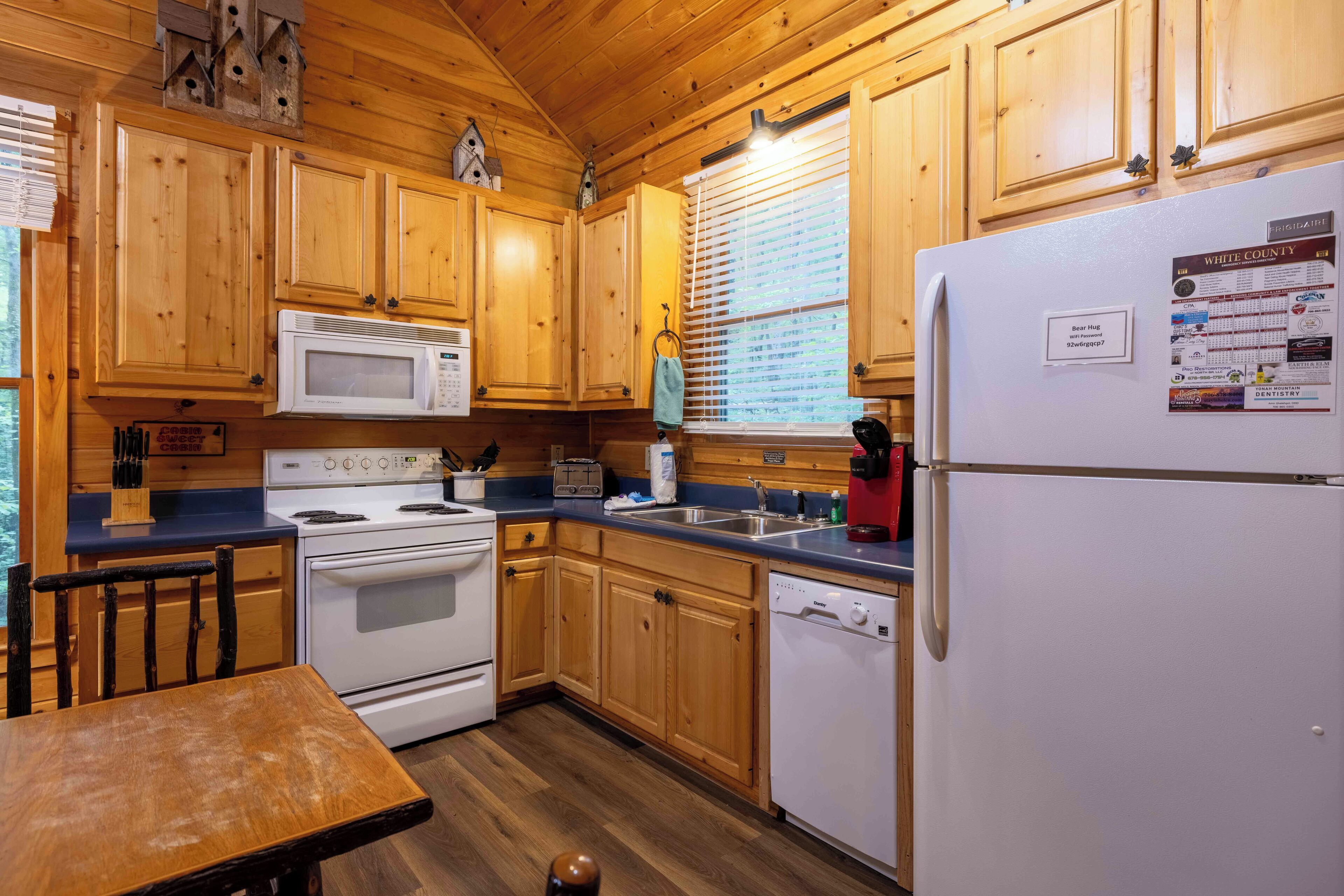 A cabin-style kitchen with wooden cabinets, a microwave, stove, and a refrigerator.