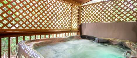 Ein Whirlpool mit Holzgitter im Hintergrund, umgeben von einer Holzterrasse.