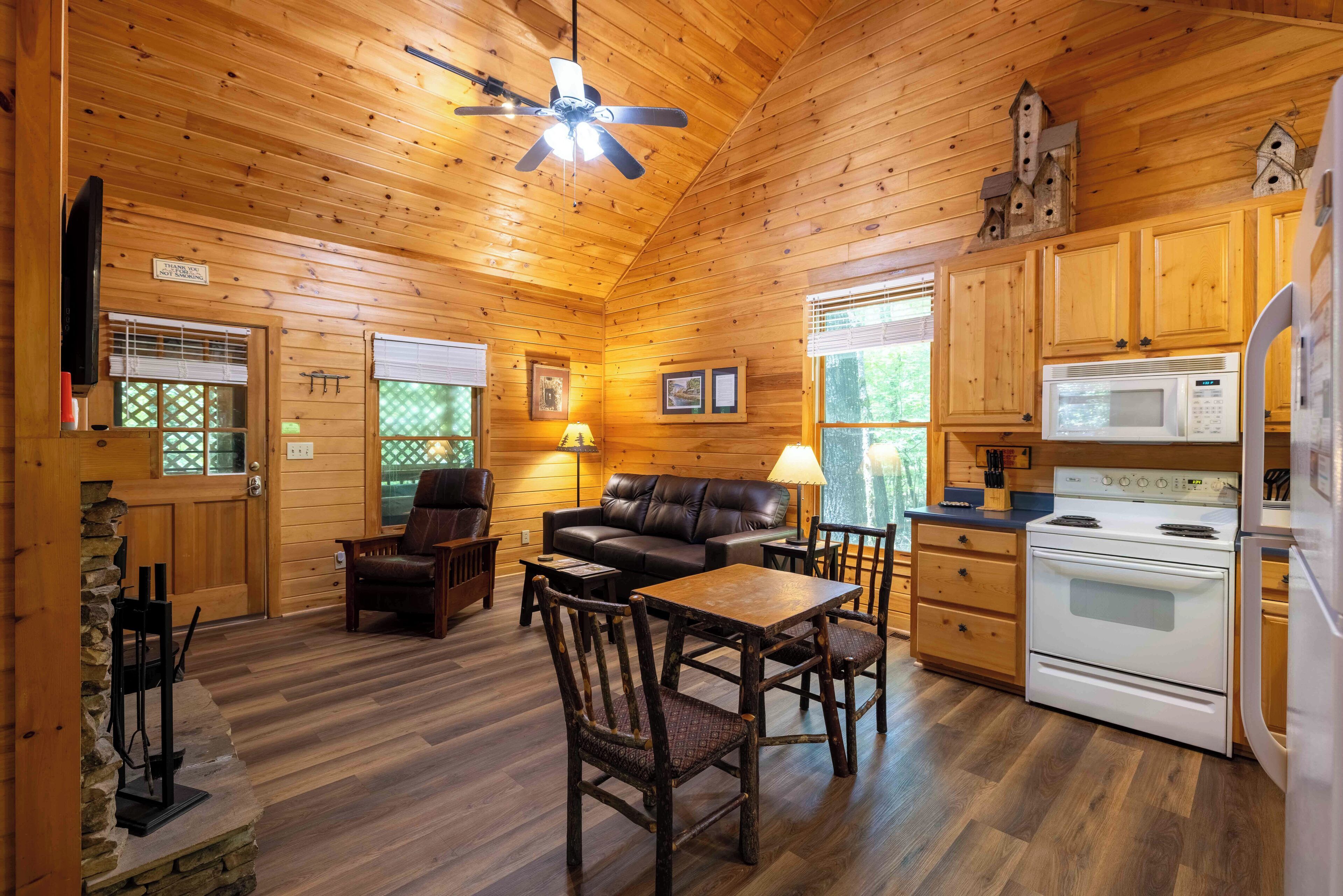 Un intérieur de chalet chaleureux, avec un revêtement en bois, une cheminée, un coin repas et une cuisine équipée d’appareils modernes.