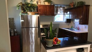 A kitchen with a stainless steel refrigerator, a black countertop, and wooden cabinets. - Vineyard Mansion - Carriage House - 1 Queen 1 Full Bed (St Joseph)